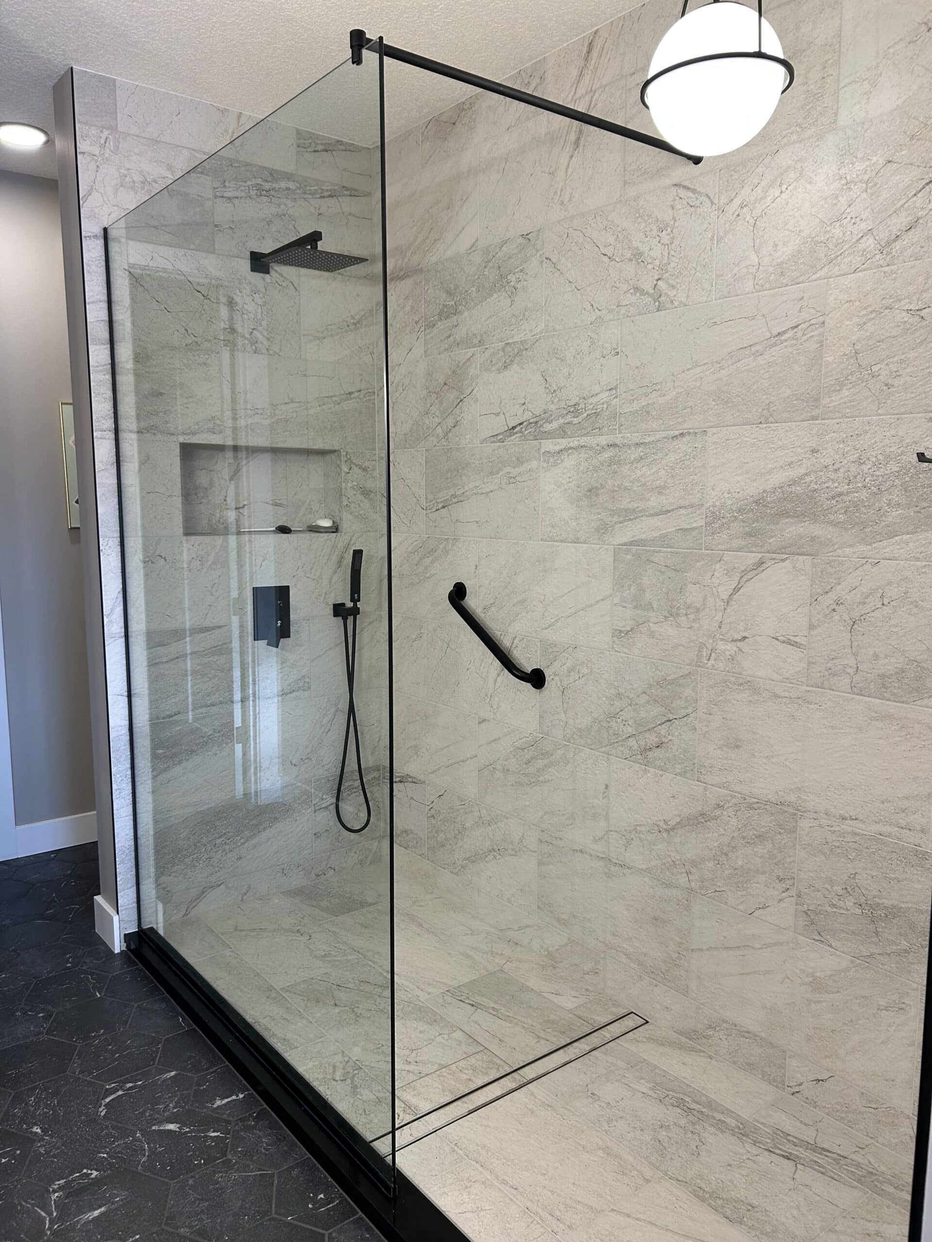 renovated shower with glass enclosure and white marble tiles