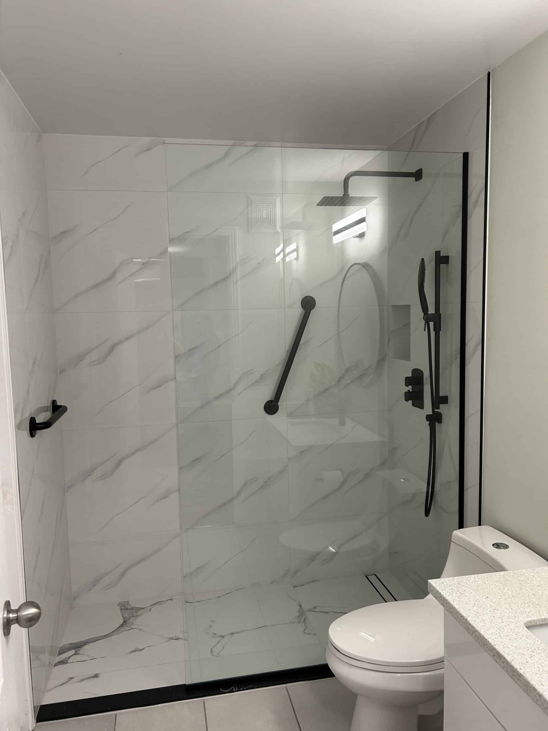 renovated shower with white marble and black fixtures
